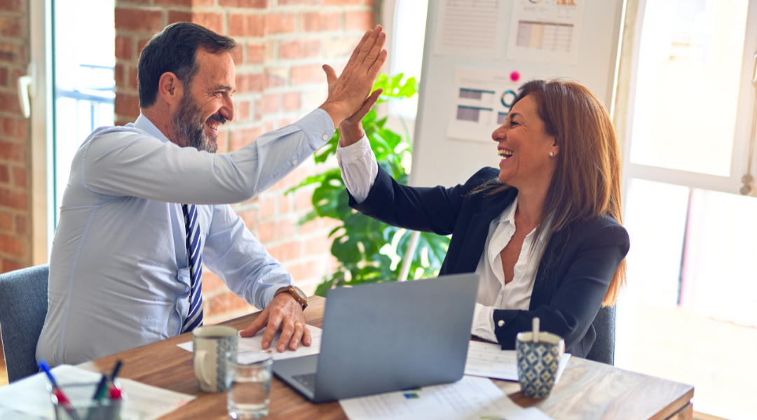 two people high fiving over computer