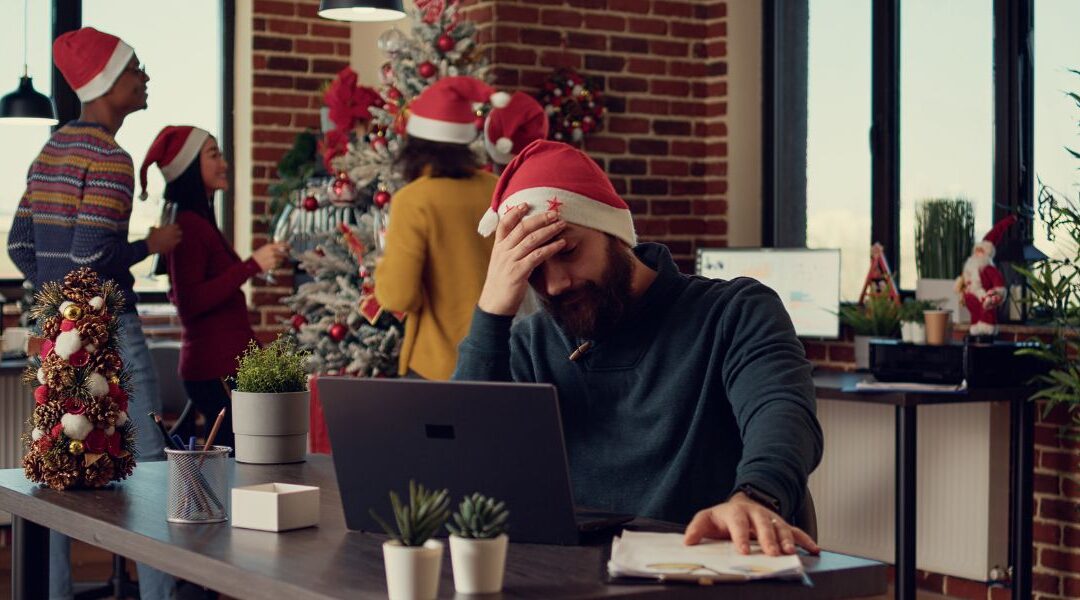 a sad man sitting at his computer during company holiday party