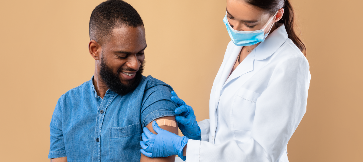 female nurse applying bandage to male employee after vaccination