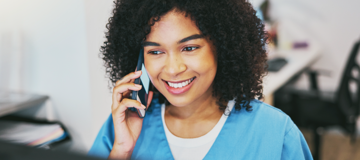 nurse on phone at desk in blue scrubs