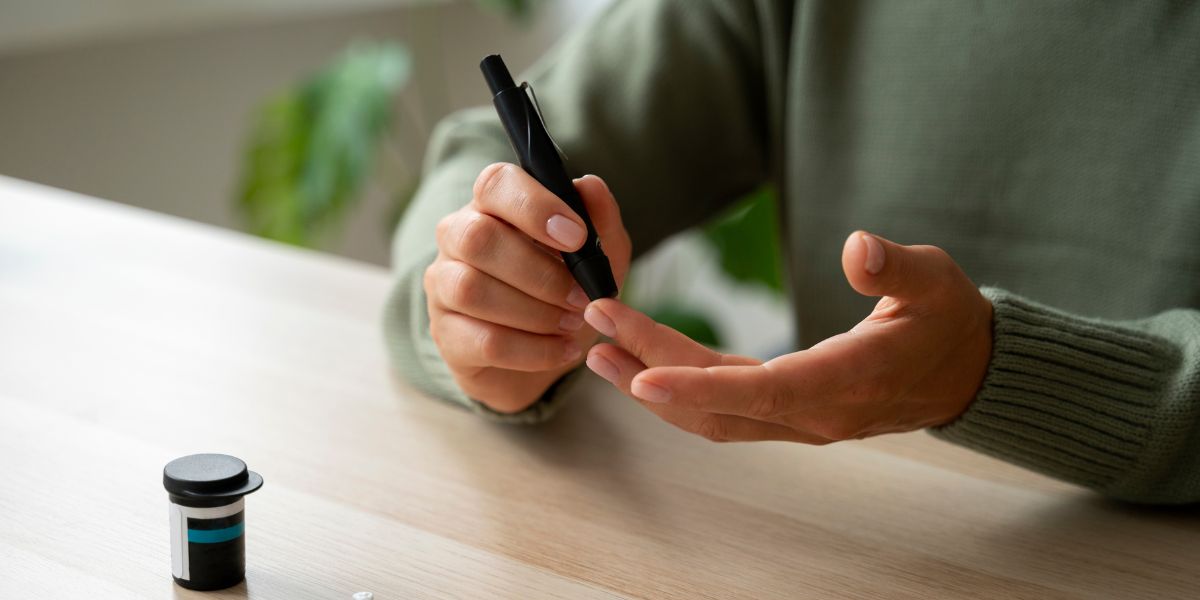 person in green sweater poking finger for diabetes test at work