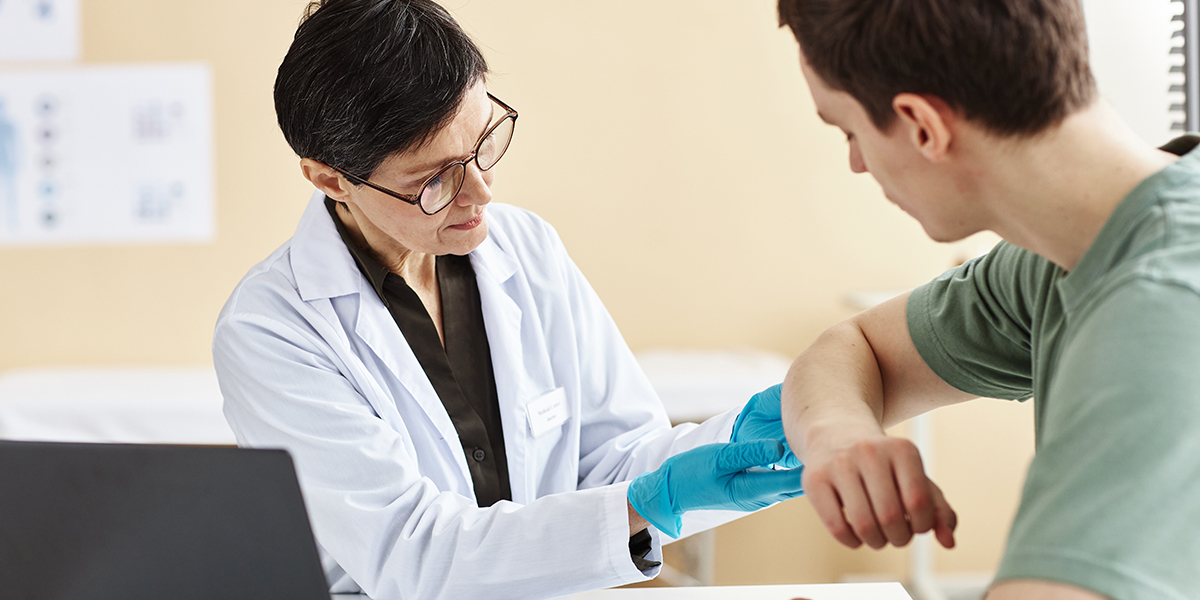 Mature female doctor inspecting patient with skin rash