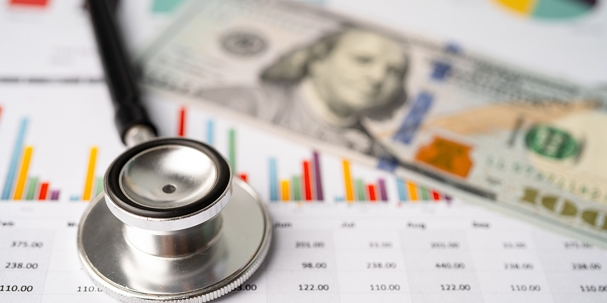 Stethoscope and US dollar banknotes on chart or graph paper