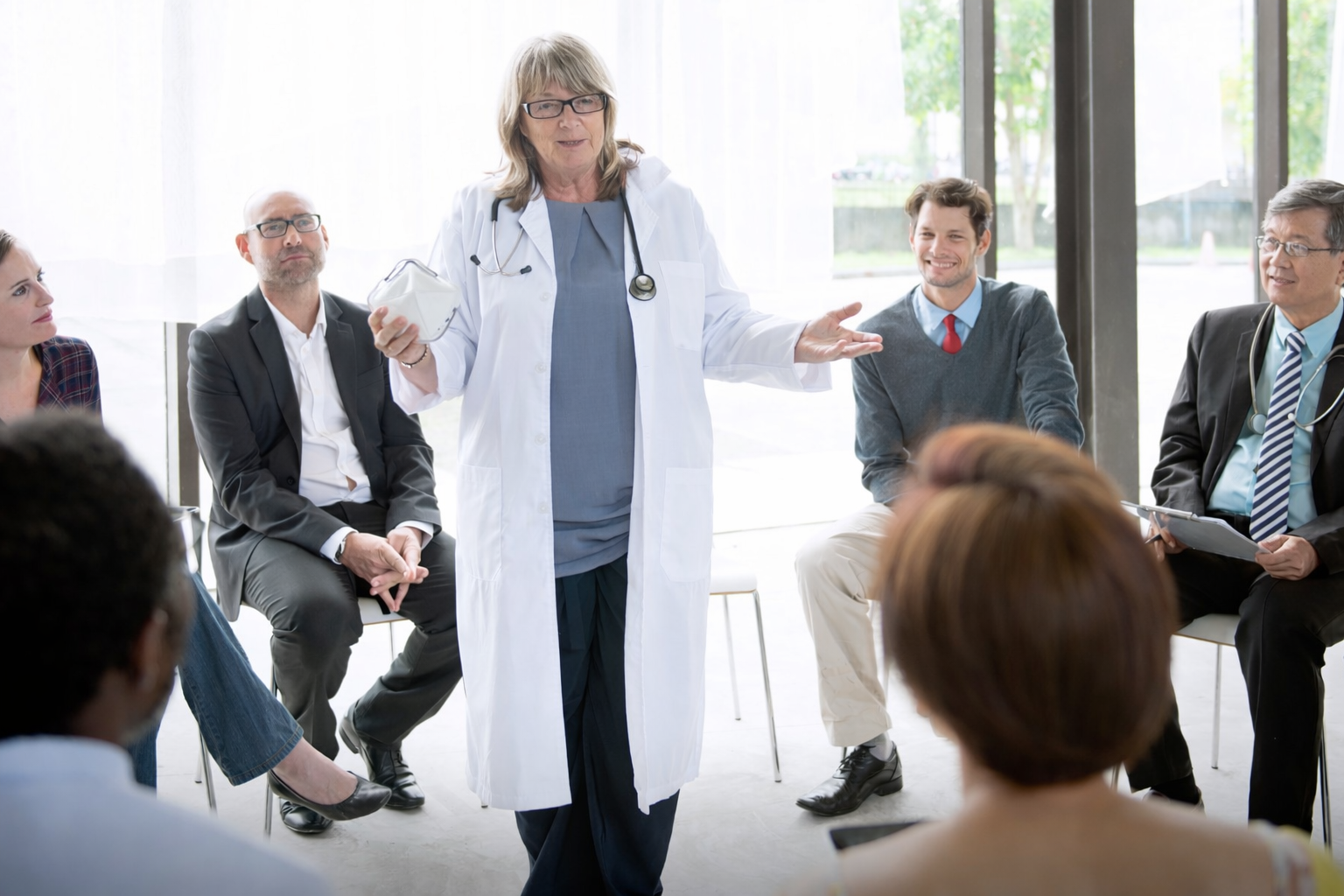 ChatGPT Image Feb 17 2026 01_58_14 PM • OnSite Health Doctor explaining how to use a n95 mask to a group of professionals